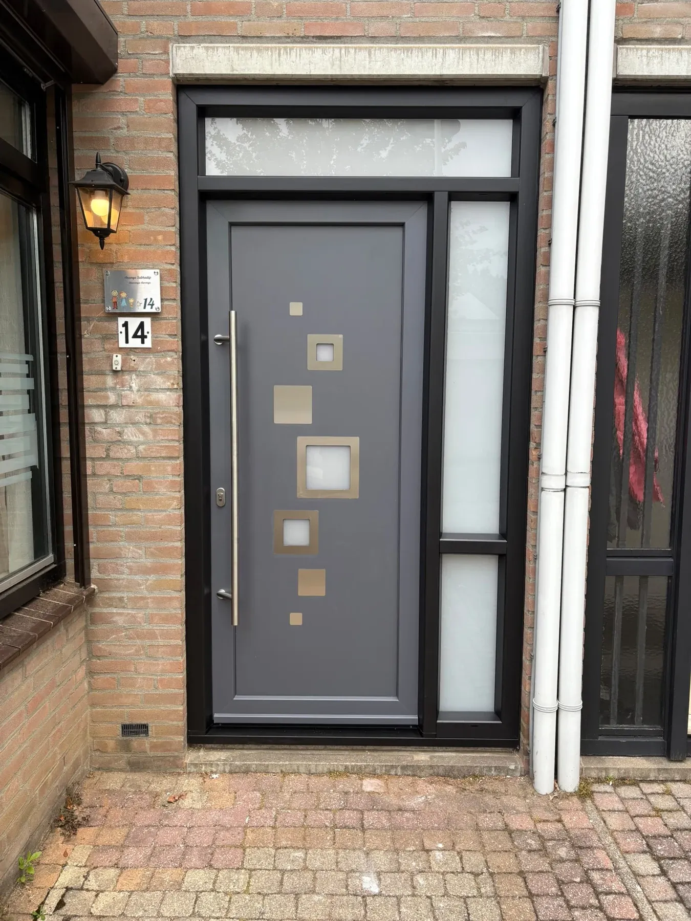 Donkere voordeur met glasdetails in een gemetselde entree